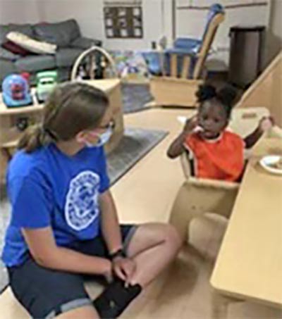 A student volunteer sitting with a young child